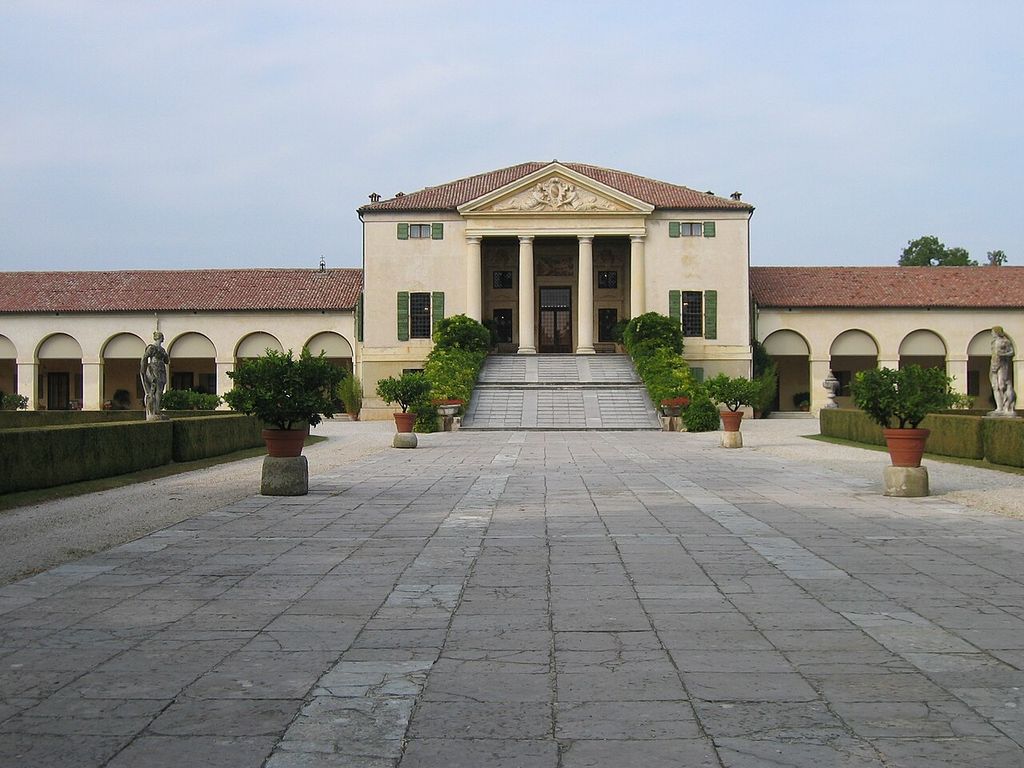 A central pedimented villa with a broad ramp is joined on both sides to long low arcades around a paved forecourt.