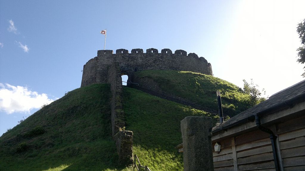 A circular stone wall crowns a grassy mound, with a stair ascending its slope.