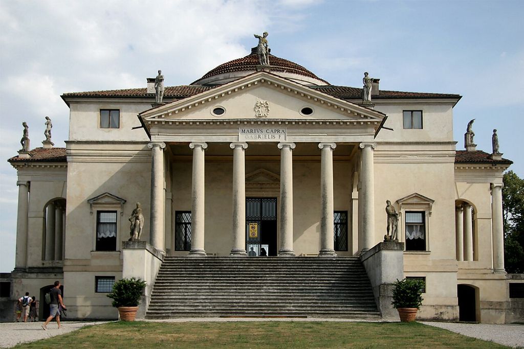 A symmetrical pale villa has a six-column portico, triangular pediment, broad stair and low dome, with statues and visitors outside.