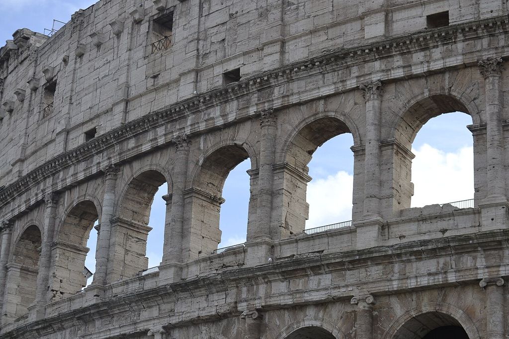A curving row of large arches is divided by engaged leafy-capital columns beneath the weathered attic wall.
