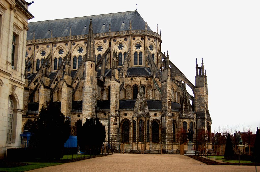 Flying buttresses cross between tall upper walls, intermediate supports and outer piers above tiers of roofs and radiating chapels.