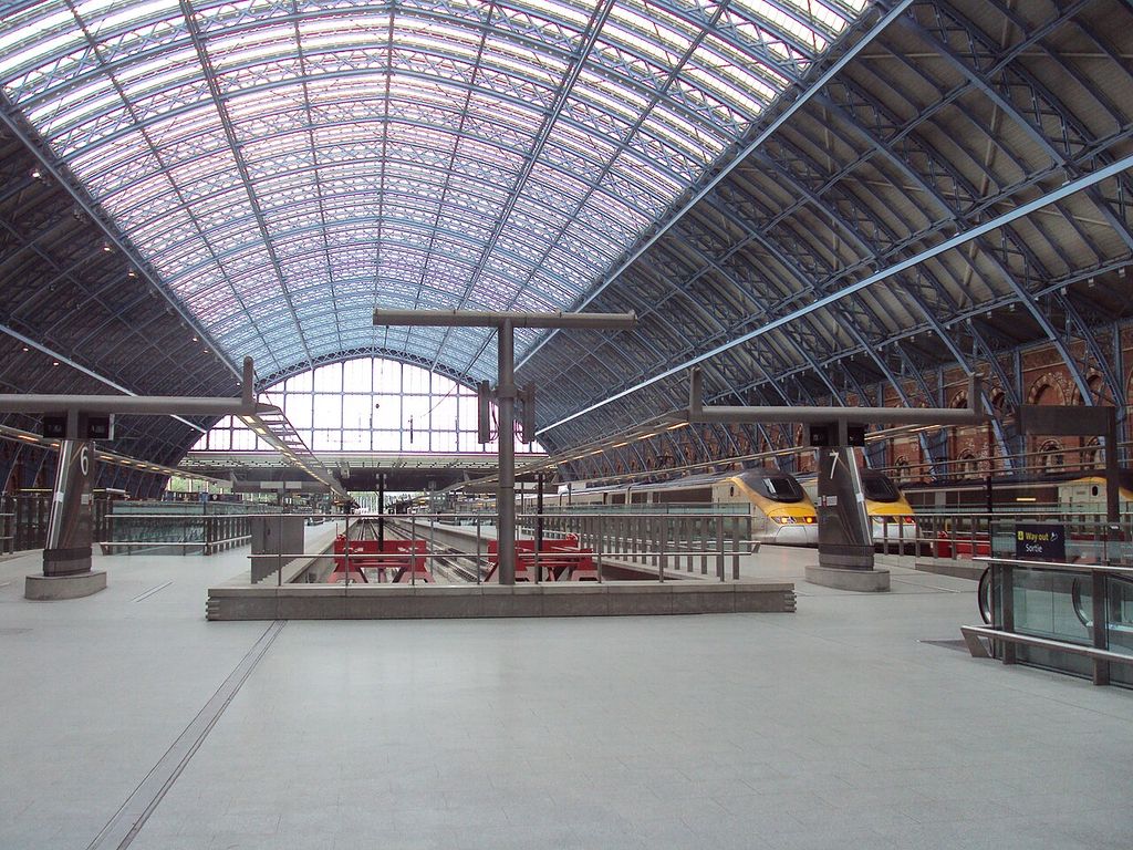 A broad arched roof with repeated metal ribs and glazing spans railway platforms.