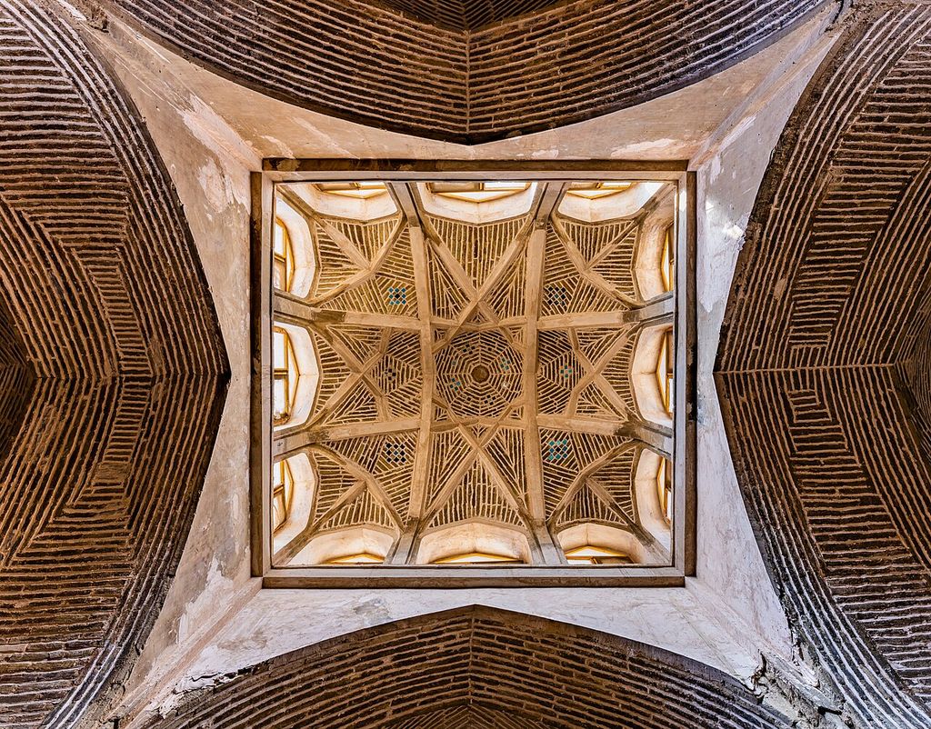 A square ceiling field contains intersecting brick ribs, triangular coursed panels and a small central geometric pattern within darker brick vaults.