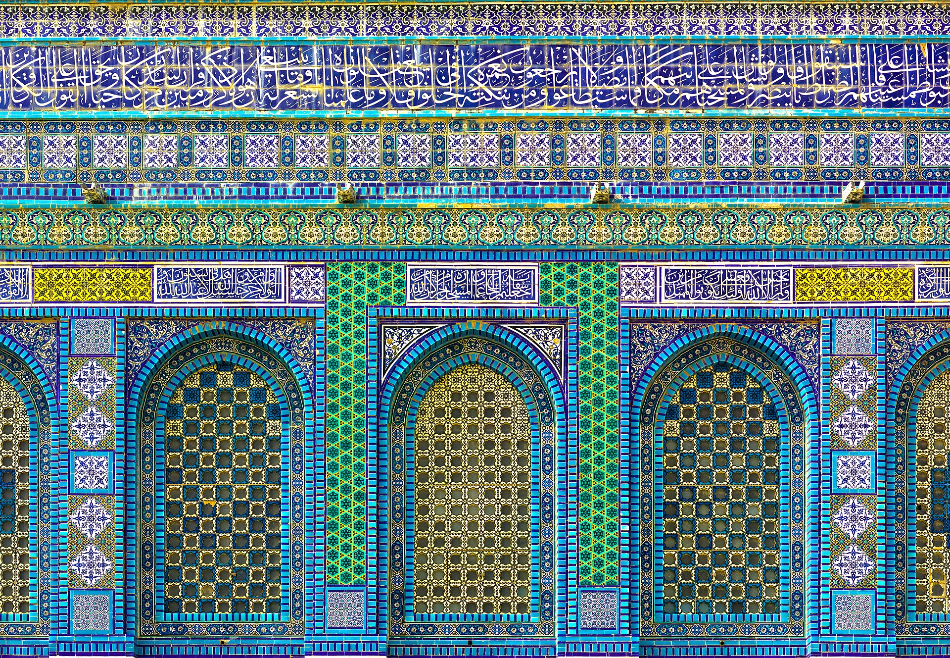 Close northeast facade showing glazed Ottoman ceramic panels, Arabic inscriptions and tall gridded windows.