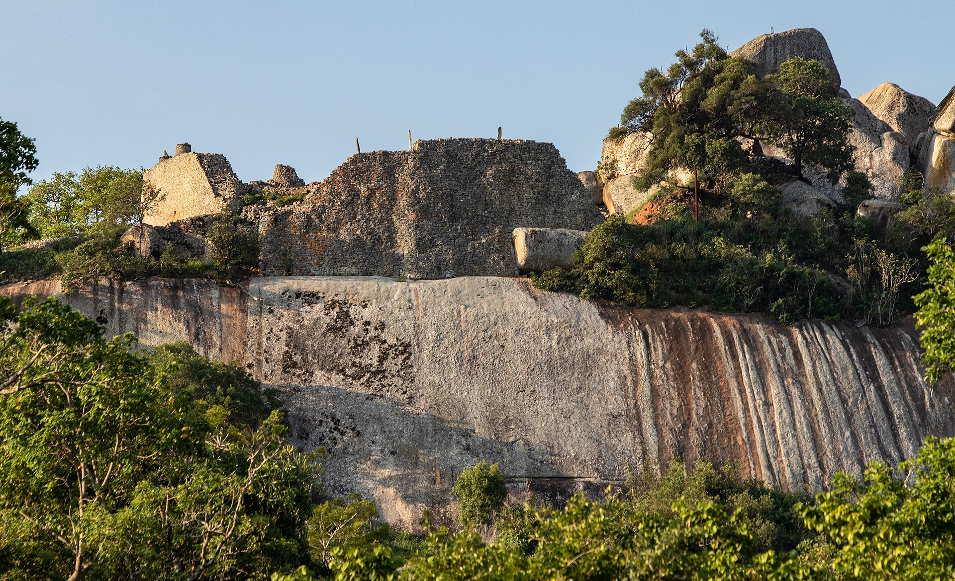 Coursed stone walls built above and beside immense rounded granite boulders on the Hill.