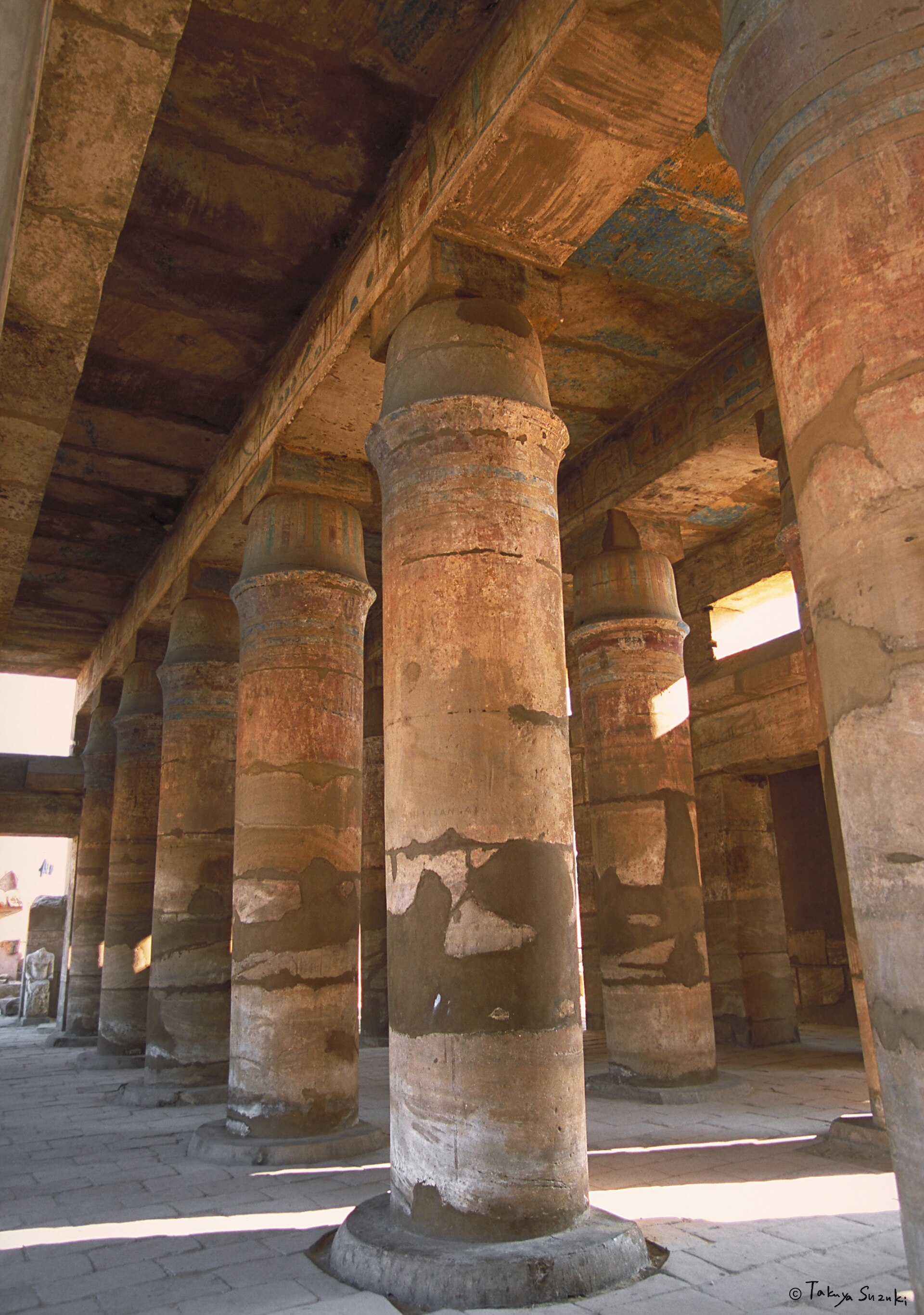 Festival Hall interior with thick tent-pole-like columns, surviving roof stones and patches of blue and red paint.
