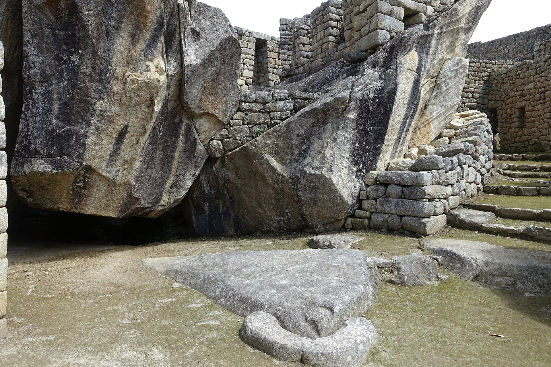 Bird-head-shaped ground stone between high natural granite rocks and adjoining masonry in the Condor complex.