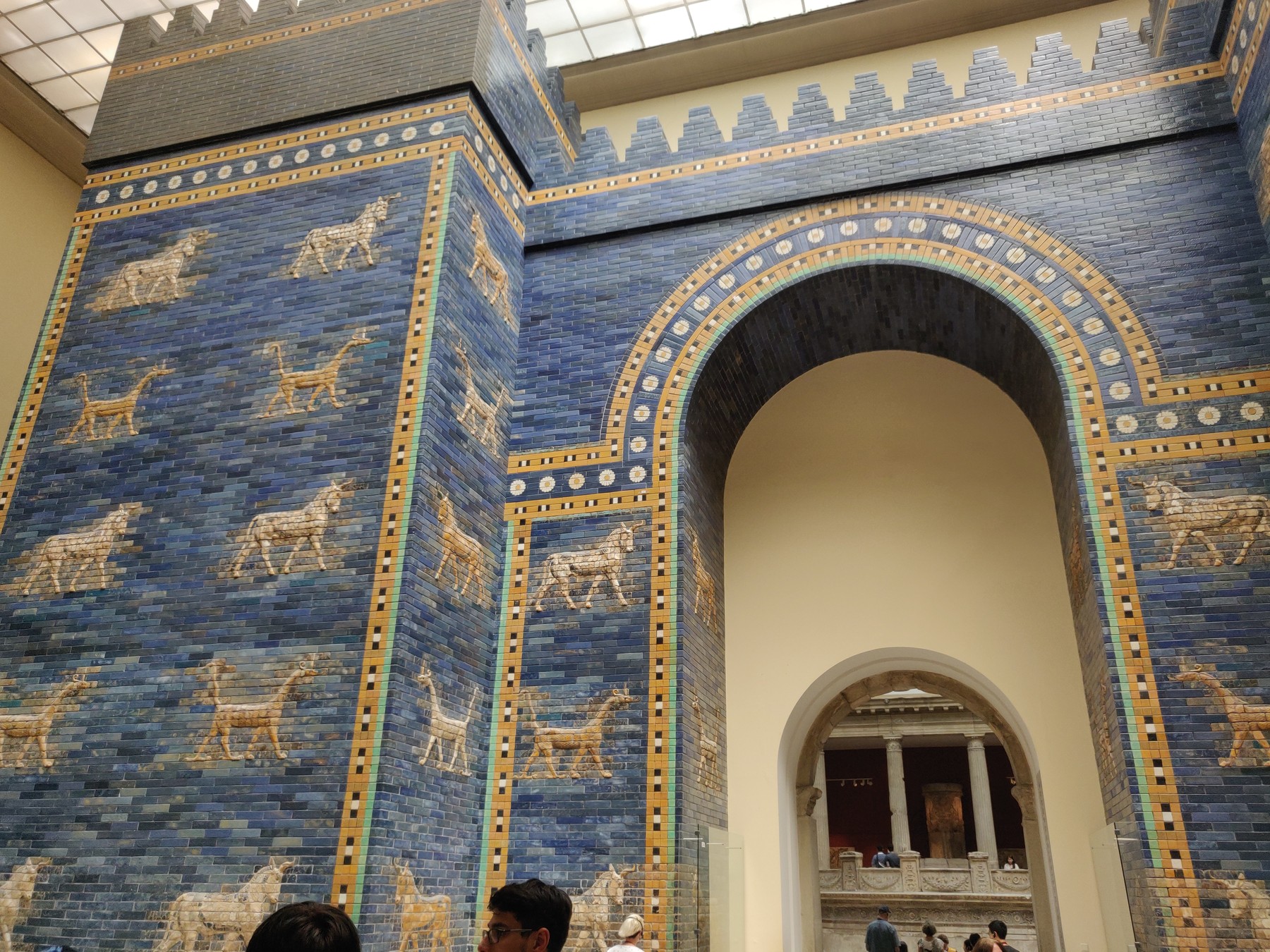 Blue glazed Ishtar Gate reconstruction with relief animals and an arched opening beneath the museum roof.