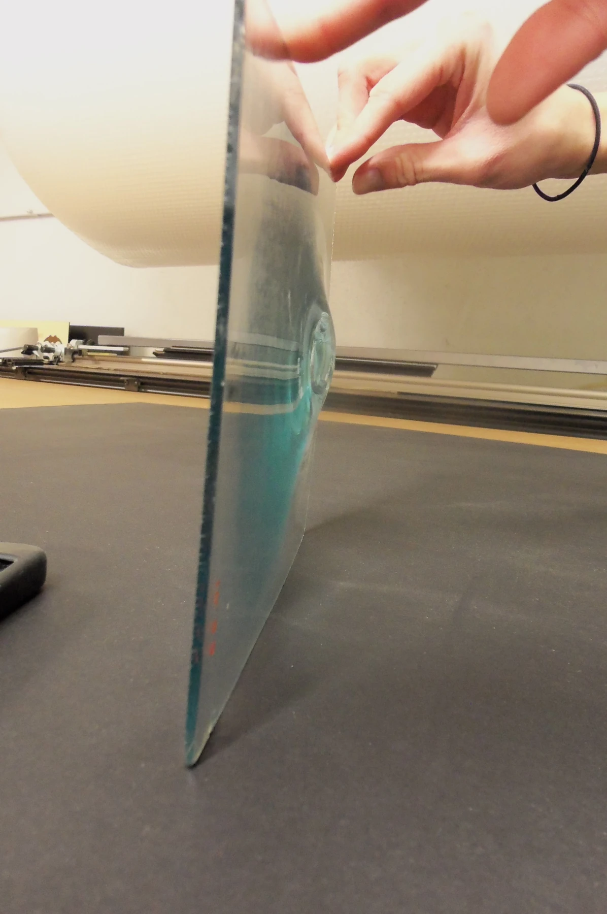 A crown-glass disc seen edge-on, with its thicker central area visible.