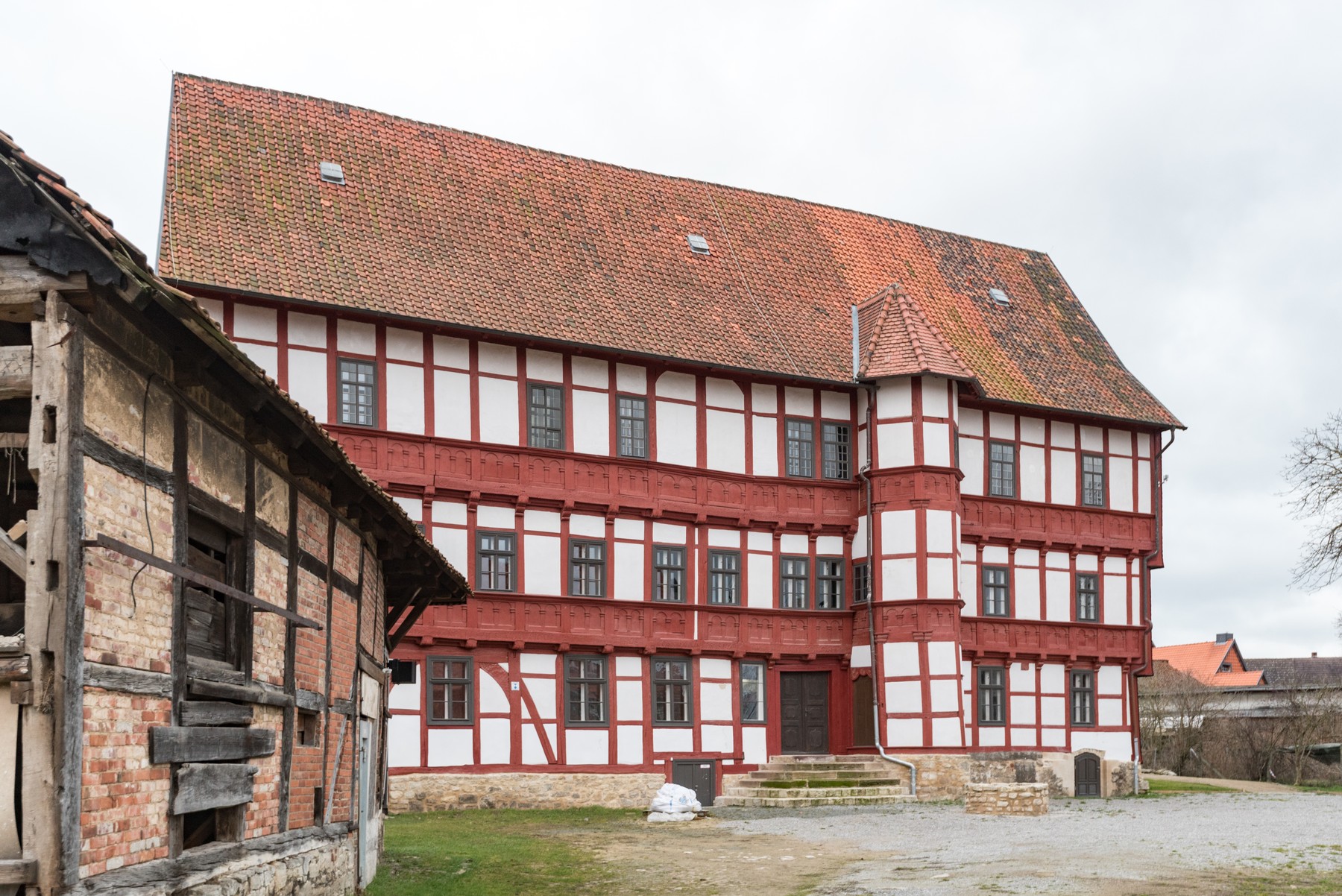 Bunter Hof in Osterwieck, with red framing, pale panels, decorated horizontal bands, a projecting bay and a stone lower base.