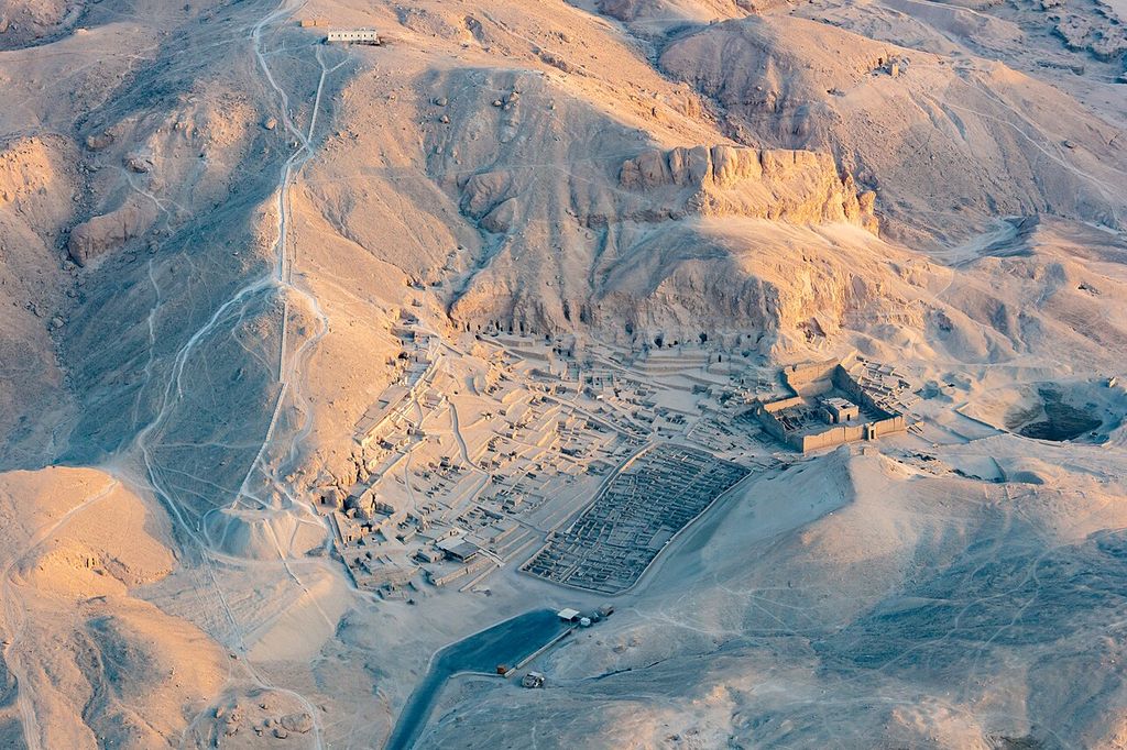 Dense rectangular house remains beside a walled temple precinct in the hills of Deir el-Medina.