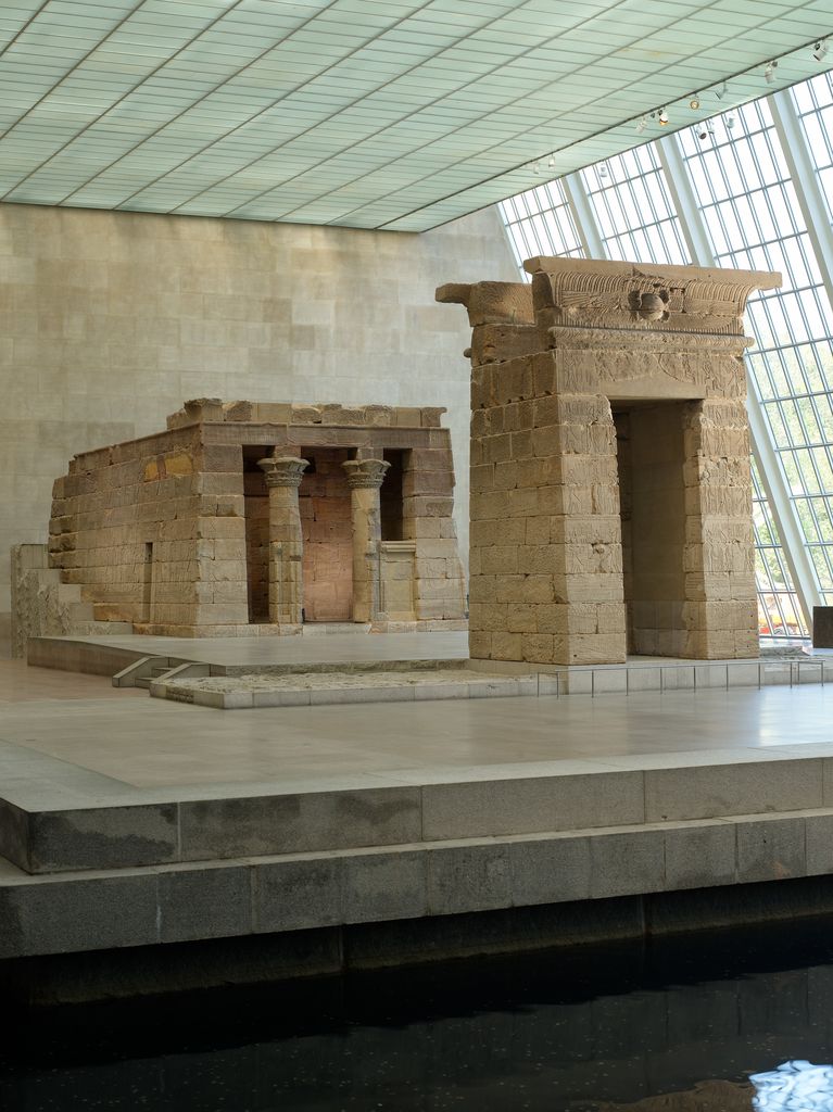 Temple of Dendur and separate gateway displayed beside water within a modern glazed museum gallery.