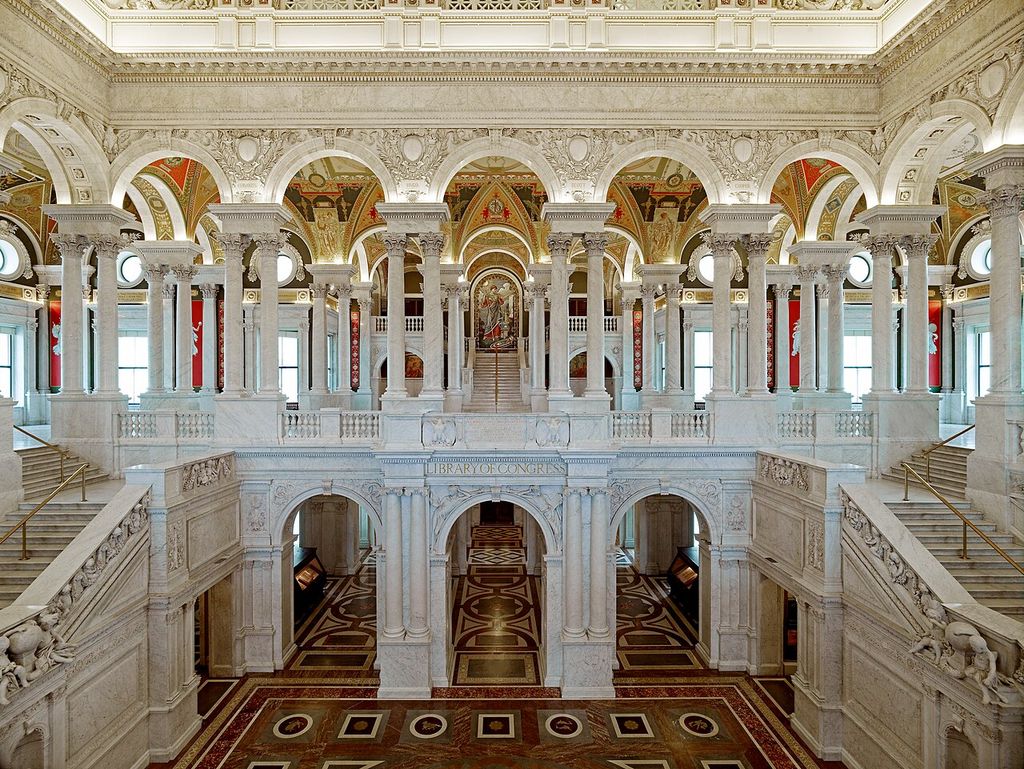 Twin marble stairs rise to two levels of columns, arches and painted decoration, with a mosaic visible beyond.