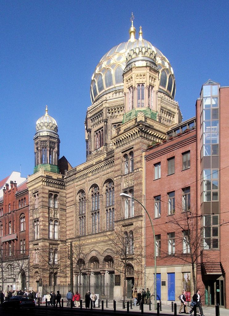 A large gilded ribbed dome and smaller domed towers rise above an ornate brick façade.