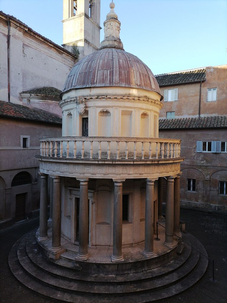 Circular colonnade and stepped base beneath a balustraded drum and dome, enclosed by courtyard buildings.