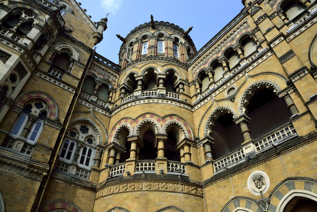 Stacked arcades and a curved bay combine carved columns, patterned stone bands and a relief frieze.