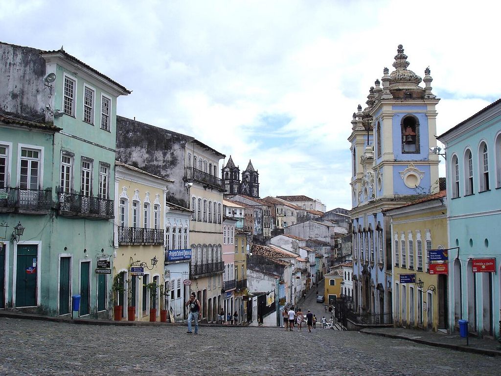 The blue church’s towers and side face a sloping public square lined with narrow multistorey buildings.