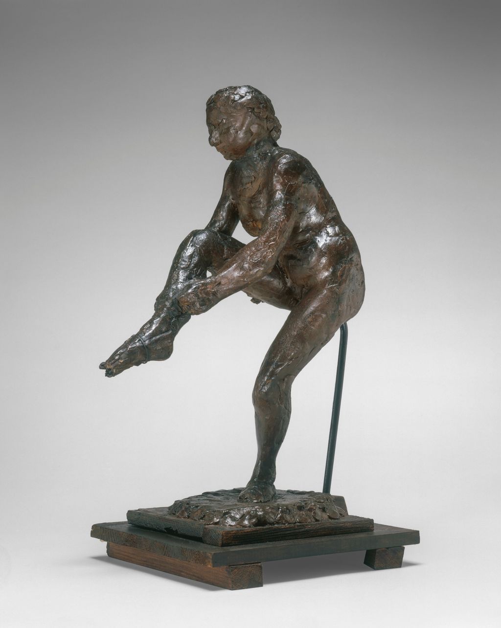 Original wax dancer bending to put on a stocking