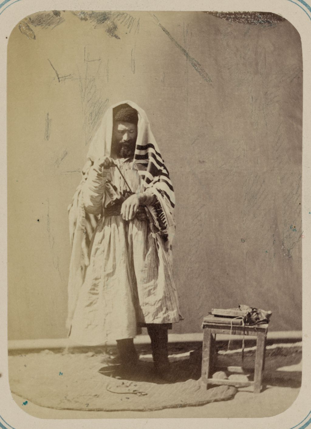 Contextual image of jewish man preparing for prayer with tallit and tefillin in samarkand.