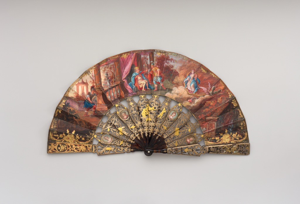 Open late eighteenth-century folding fan with a painted semicircular paper leaf supported by decorated sticks.