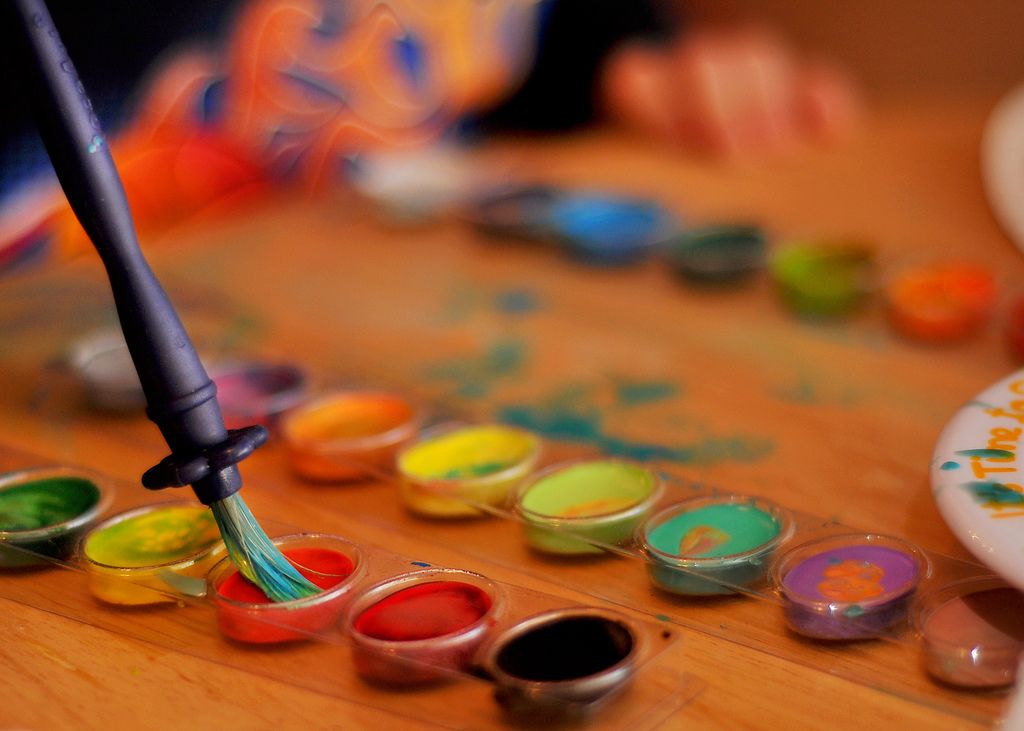 A pointed brush being loaded from a set of watercolour pans.