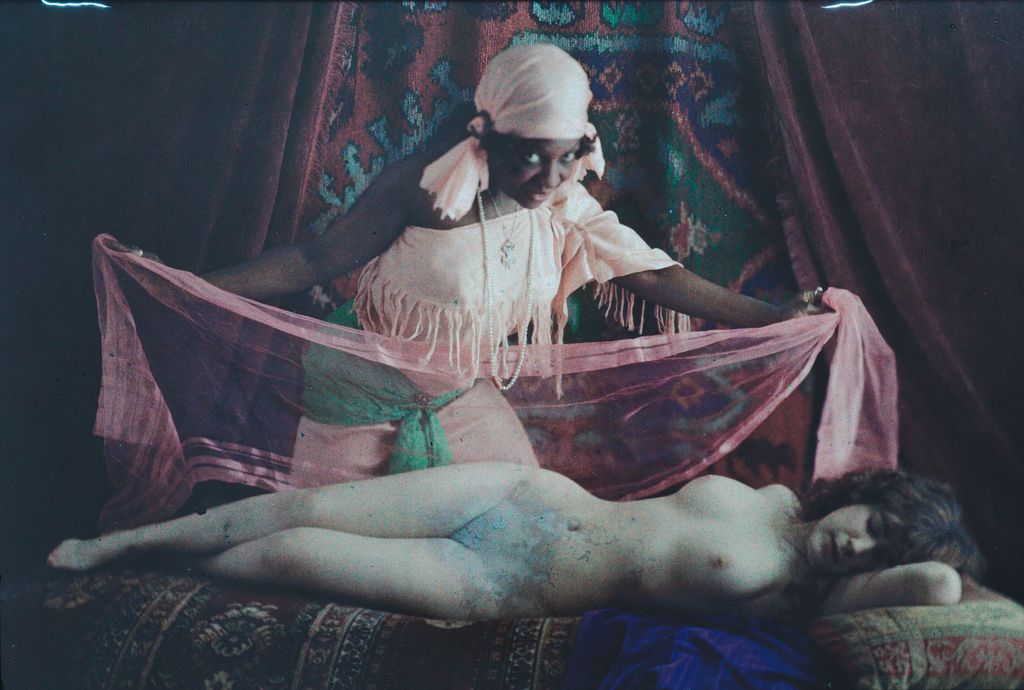 A dark grainy Autochrome shows a reclining nude and seated figure among pink, green, blue and pale fabrics.