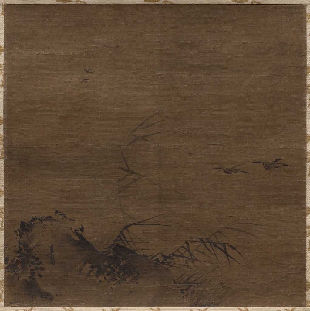 Dark and diluted ink marks cluster in one lower corner of aged silk, leaving broad open support around reeds, rock and flying birds.