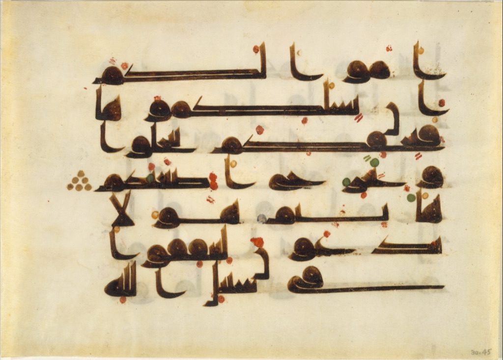 A complete parchment Qur'an folio carries broad dark lines of Arabic script with small gold details.