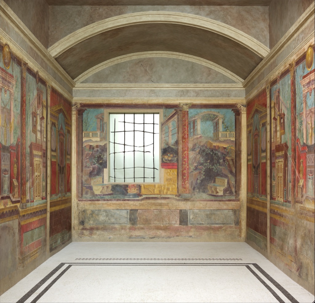 The reconstructed Boscoreale bedroom surrounds a real floor and ceiling with painted columns, balconies and landscape openings across three walls.