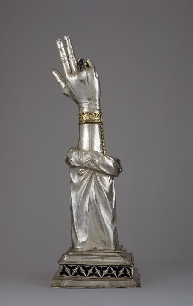 A silver and gilded-silver arm reliquary raises its jeweled hand in blessing.