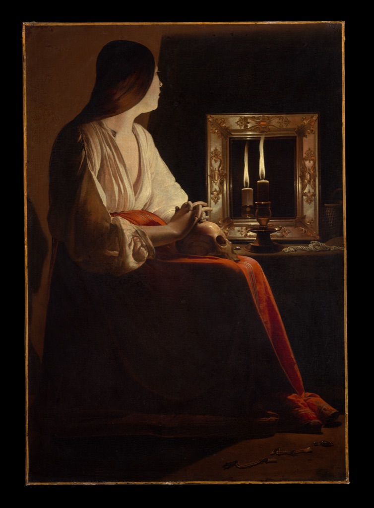 La Tour's Penitent Magdalen sits in profile beside a candlelit mirror, with her face, hands and skull emerging from a broad dark field.
