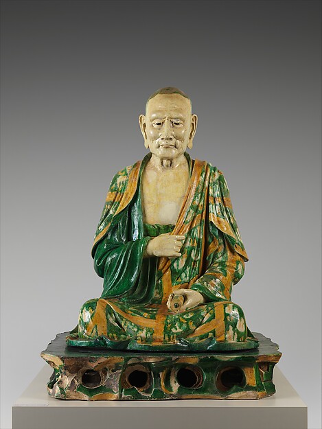 Life-size seated Chinese arhat modelled in stoneware and covered with three-colour glaze.