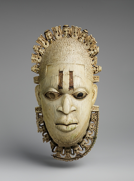 Edo ivory pendant mask of Queen Mother Idia with metal inlays and a patterned crown.